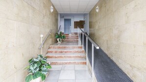 A staircase with marble walls and a metal handrail, leading to a door with a blue frame. - A&N Yecla Torre del Mar (Torre del Mar)