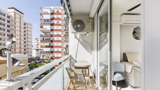 A balcony with a table and chairs, a ceiling fan, and a view of a tall building with balconies. - A&N Yecla Torre del Mar (Torre del Mar)