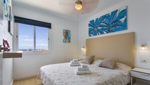 A bedroom with a bed, a nightstand, a window with a view, and artwork on the walls. - Vacation 'Lovely Nice Los Cristianos' with Sea View, Shared Pool and Wi-Fi (Los Cristianos)