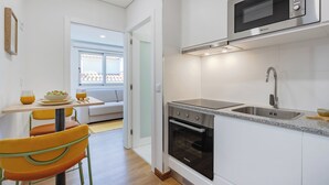 A modern kitchen with white cabinets, a built-in oven, a microwave, and a sink. - Matosinhos Coastal Studio (Matosinhos)