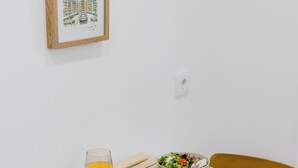 A dining table with plates, glasses, and cutlery, a framed artwork on the wall, and a yellow chair. - Matosinhos Coastal Studio (Matosinhos)