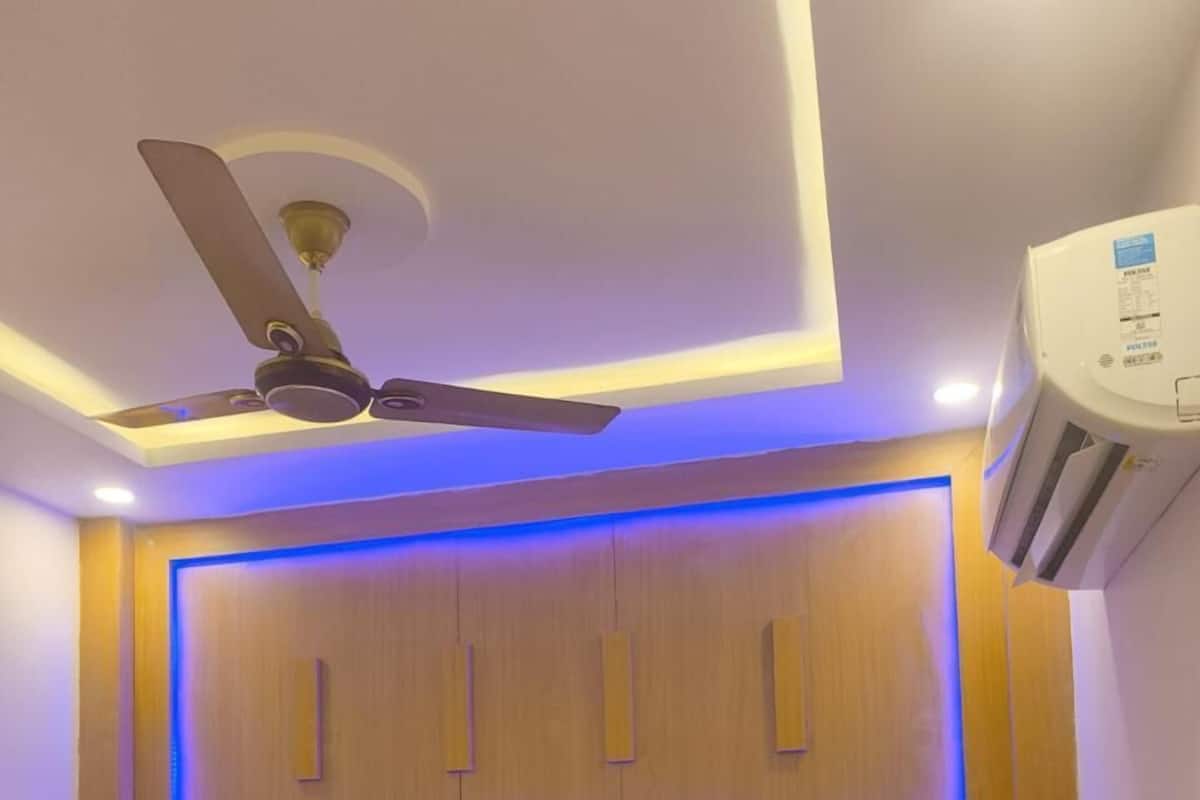 Une chambre d’hôtel équipée d’un lit, d’un ventilateur de plafond et d’un climatiseur fixé au mur.