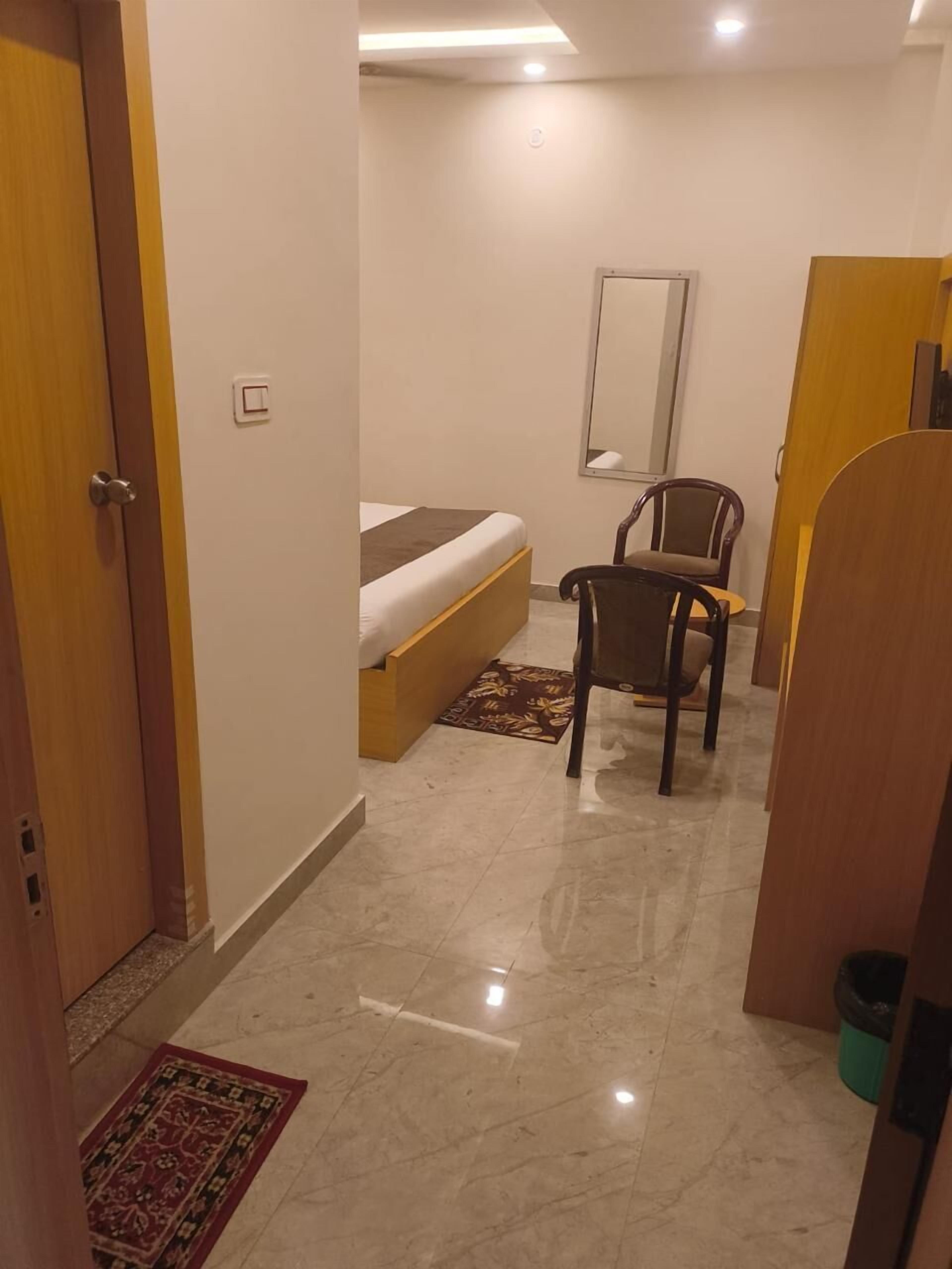 Ein Hotelzimmer mit einem Bett, einem Sessel, einem kleinen Tisch, einem Spiegel und einem Mülleimer.