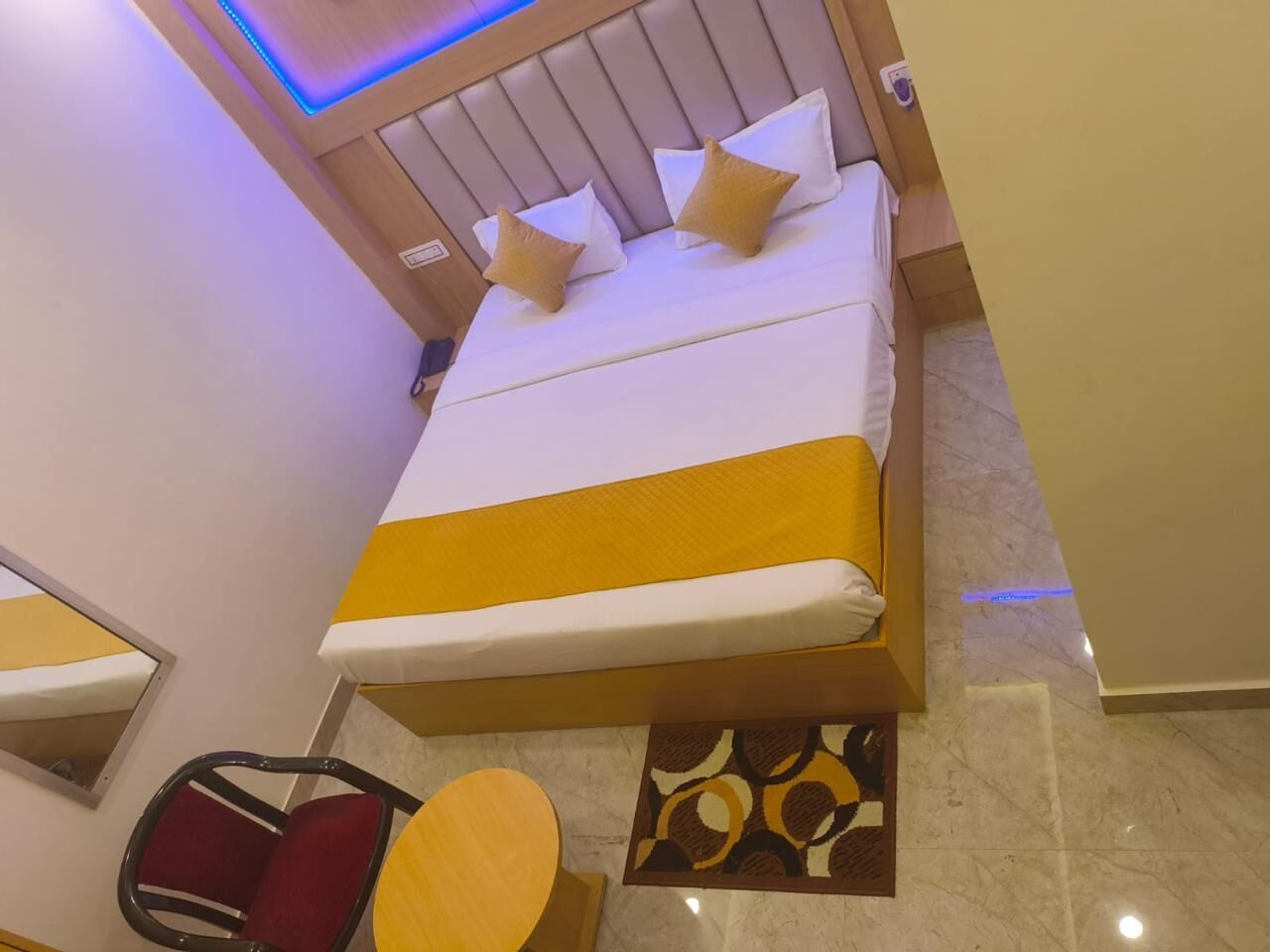Una habitación de hotel moderna con una cama, una mesita y una silla.