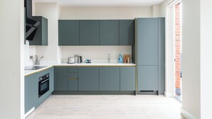 Une cuisine moderne avec des meubles de couleur turquoise, un plan de travail blanc et un four encastré.