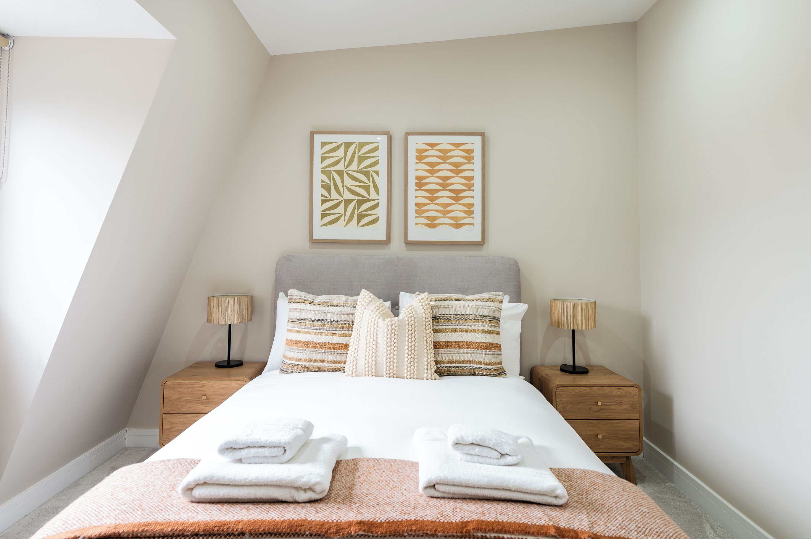 Quarto bem arrumado com uma cama, duas mesas de cabeceira e duas luminárias de parede.