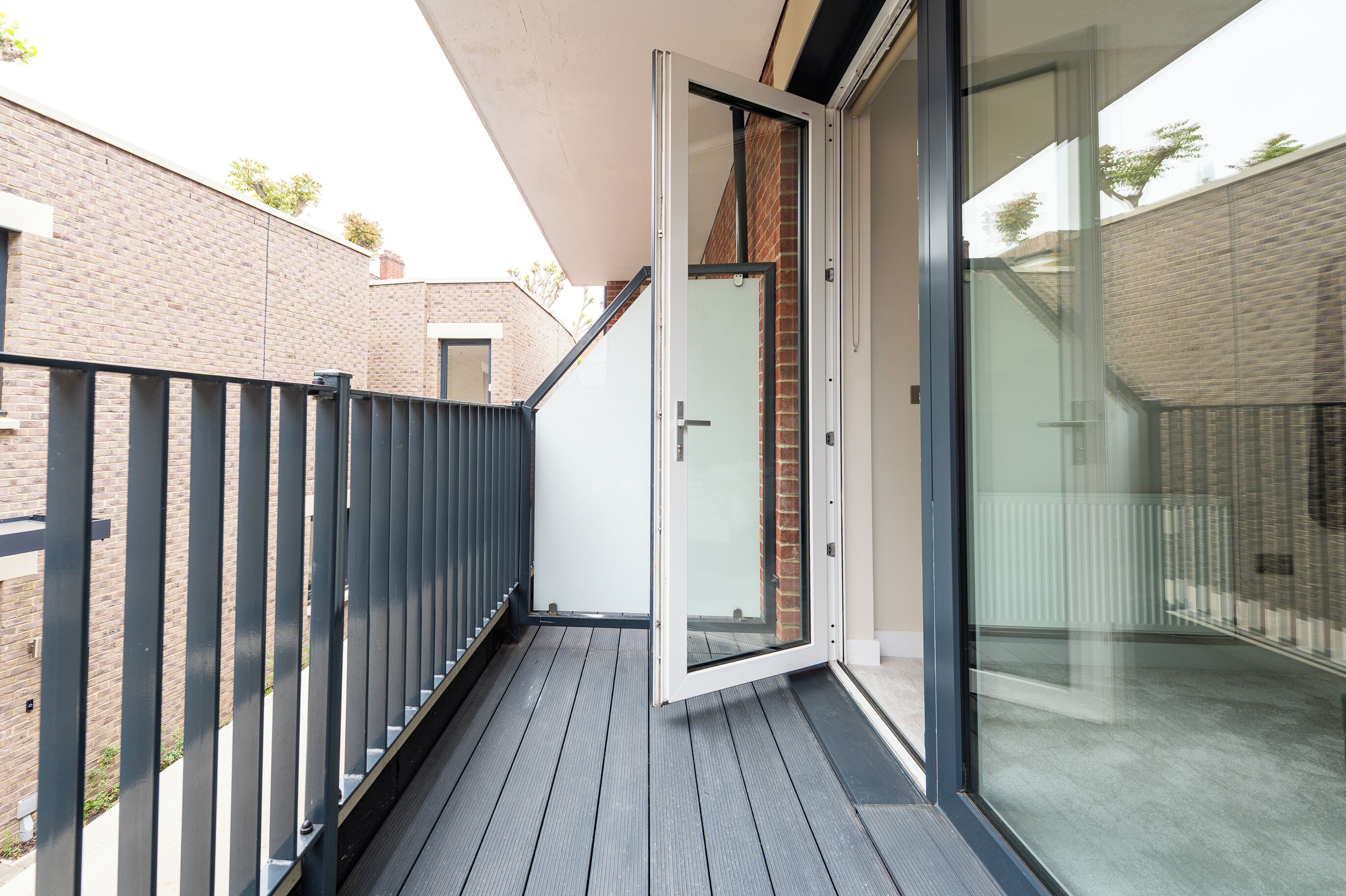 A balcony with a glass door leading to a brick wall.