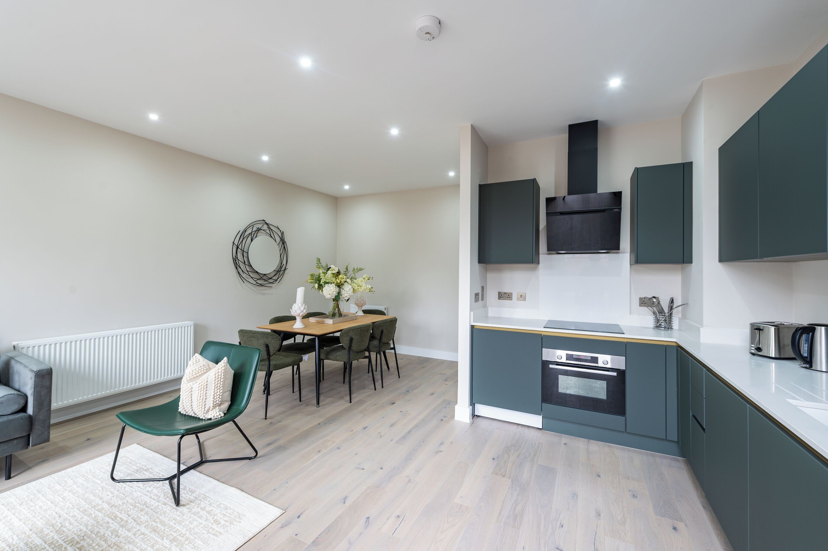 A modern kitchen with a central island, built-in appliances, and a dining area with a table and chairs.