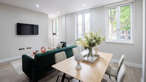 Un salon moderne avec un canapé vert, une table à manger en bois et une grande fenêtre.
