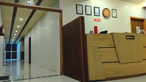 A reception area with a wooden desk, framed certificates on the wall, and a clock. - R Narayan Pleasant Inn Hotel - Guptkashi (Ukhimath)