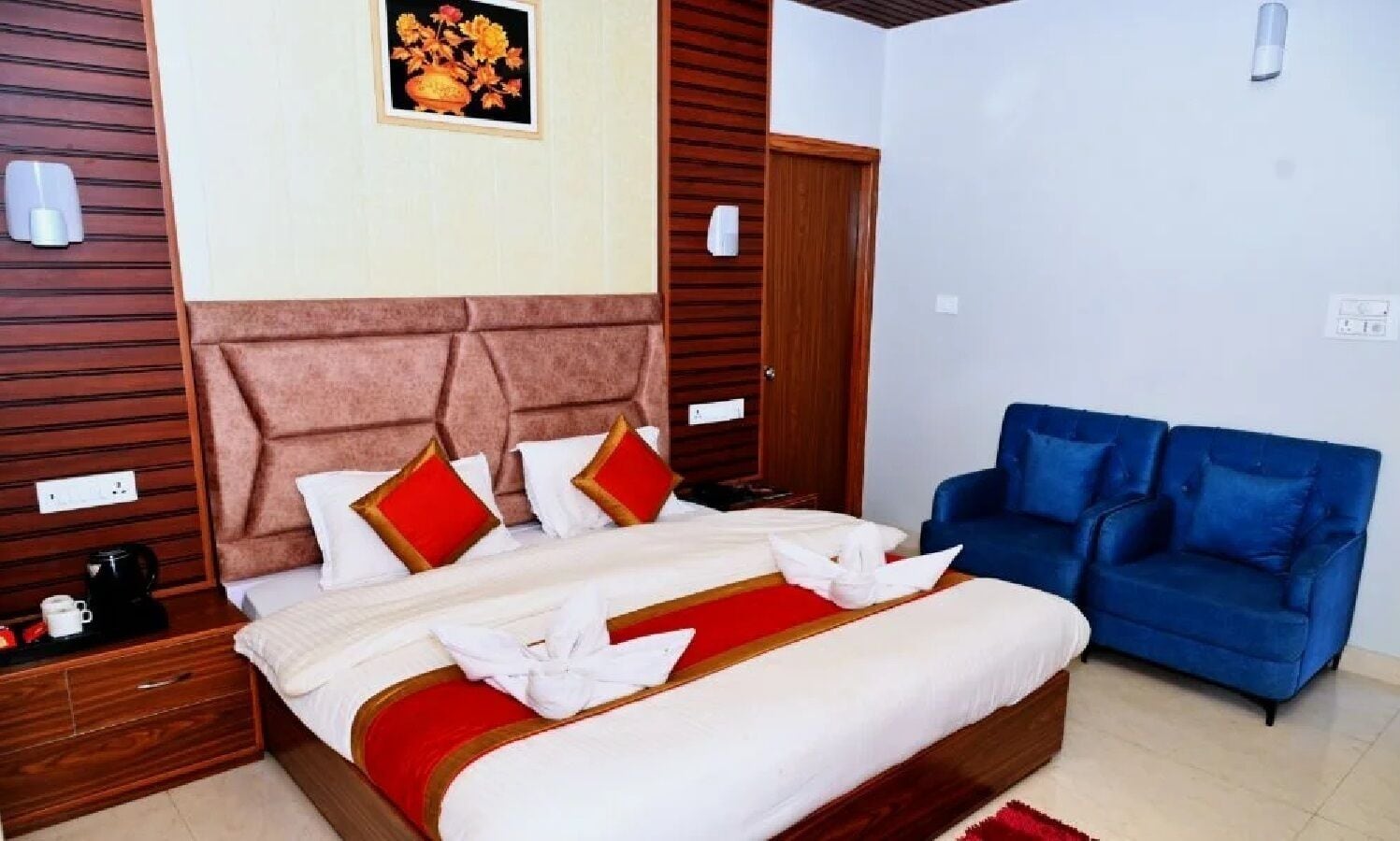 A hotel room with a large bed, a blue sofa, wooden paneling on the walls, and a framed picture on the wall.