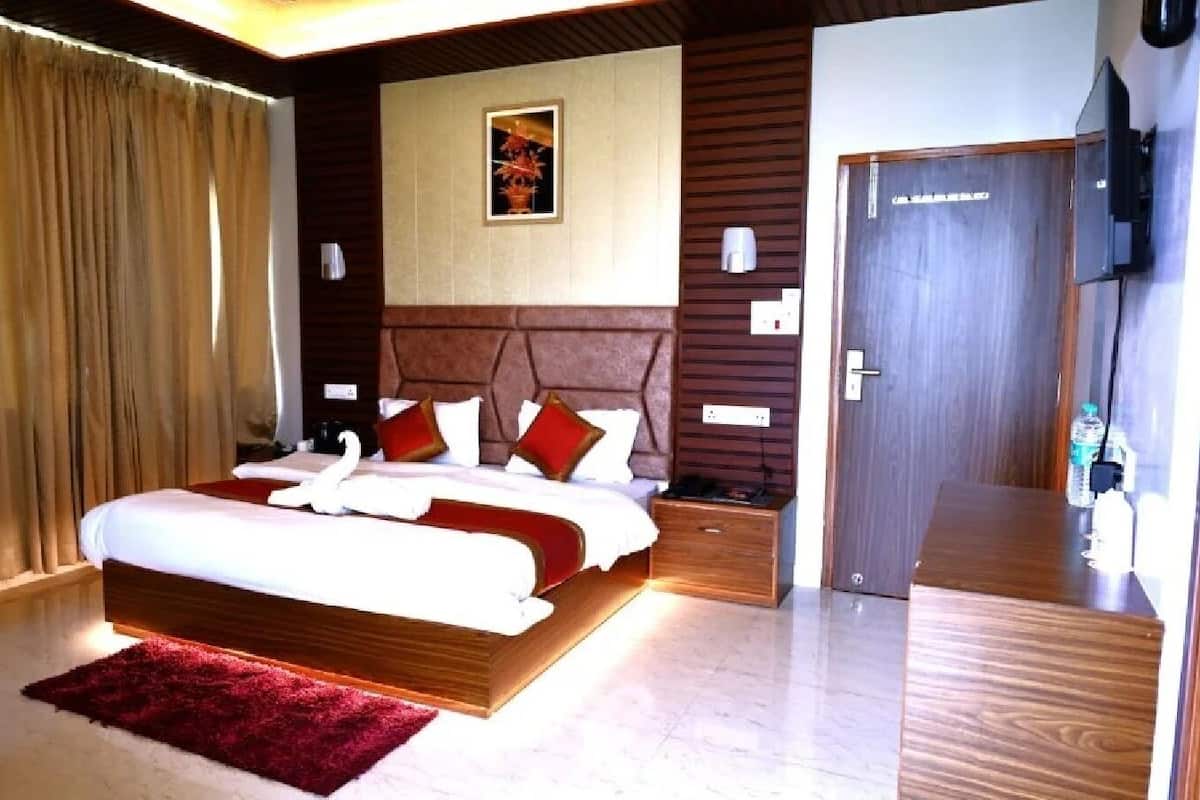 A modern hotel room with a large bed, wooden headboard, a red rug, a flat-screen TV, and a wooden door.