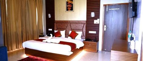 Een moderne hotelkamer met een groot bed, een houten hoofdeinde, een rood vloerkleed, een flatscreen televisie en een houten deur.