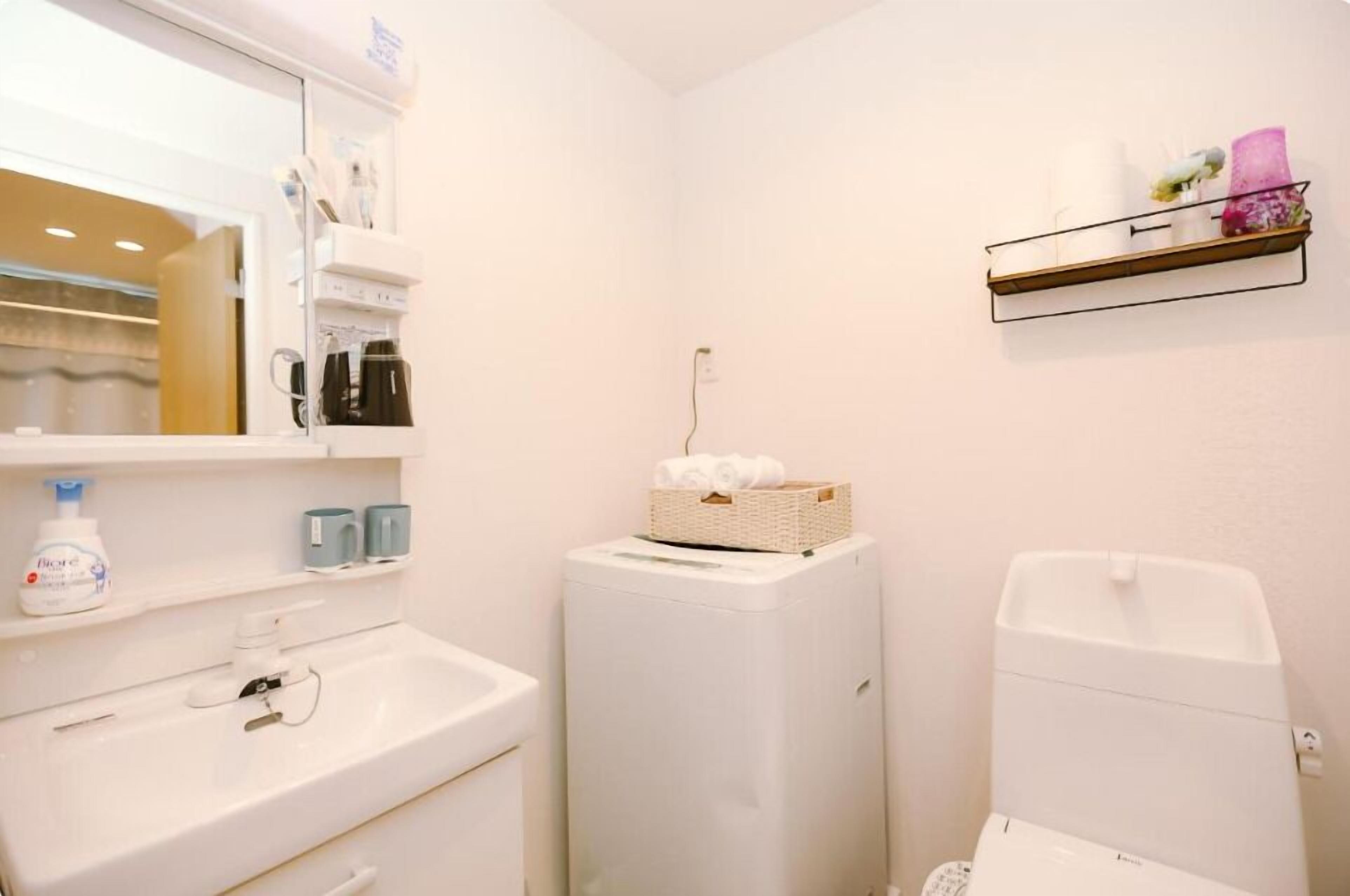Un bagno piccolo con un lavandino bianco, uno specchio, un water bianco e uno scaffale con articoli da toilette.