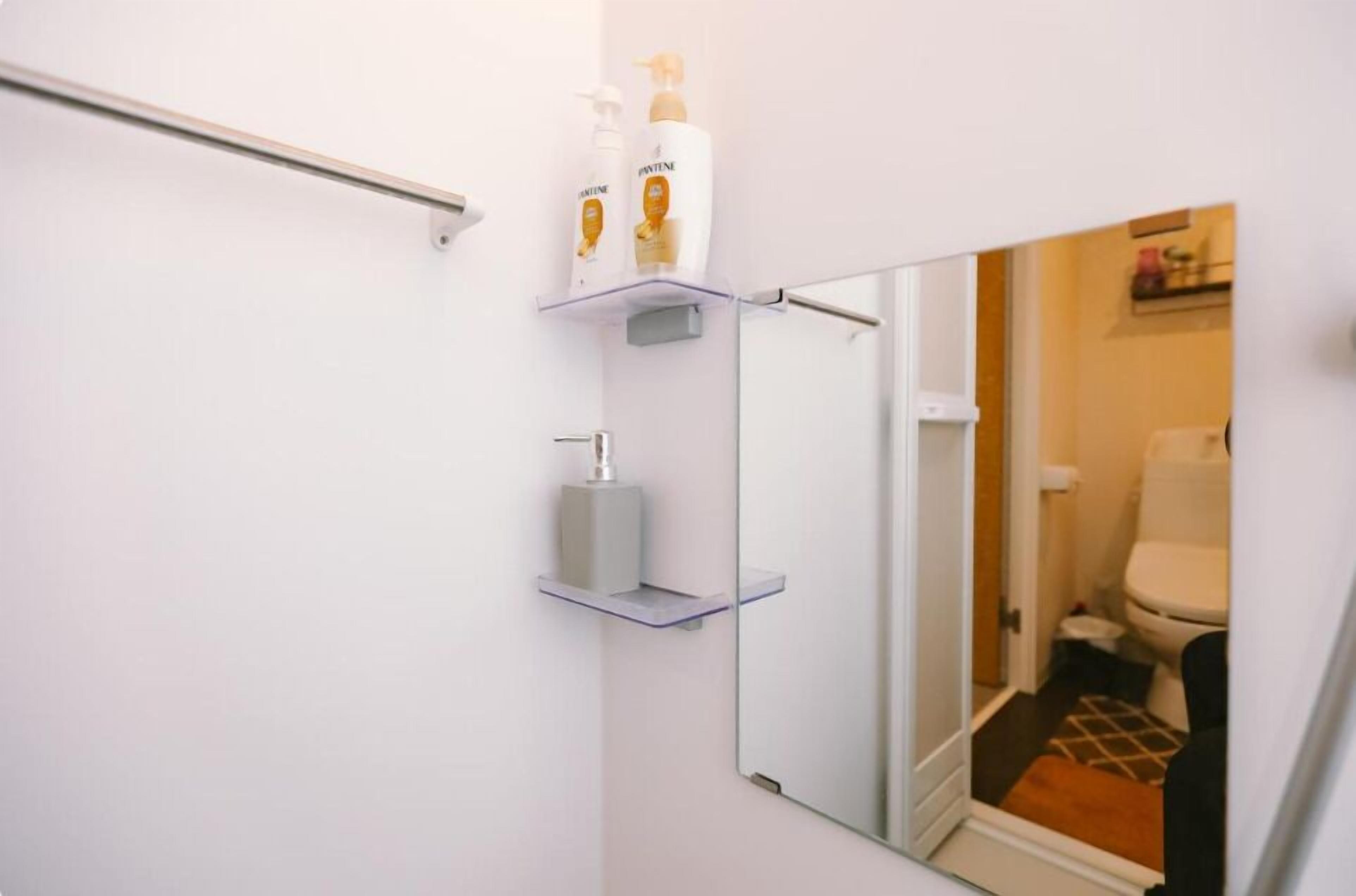 Ein Badezimmer mit Spiegel, zwei Ablagen mit Toilettenartikeln und einer im Spiegel sichtbaren Toilette.