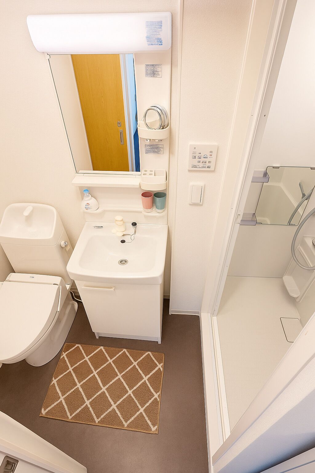 A compact bathroom with a toilet, sink, and shower.