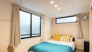 Un dormitorio con cama, cortinas, un reloj y un escritorio.