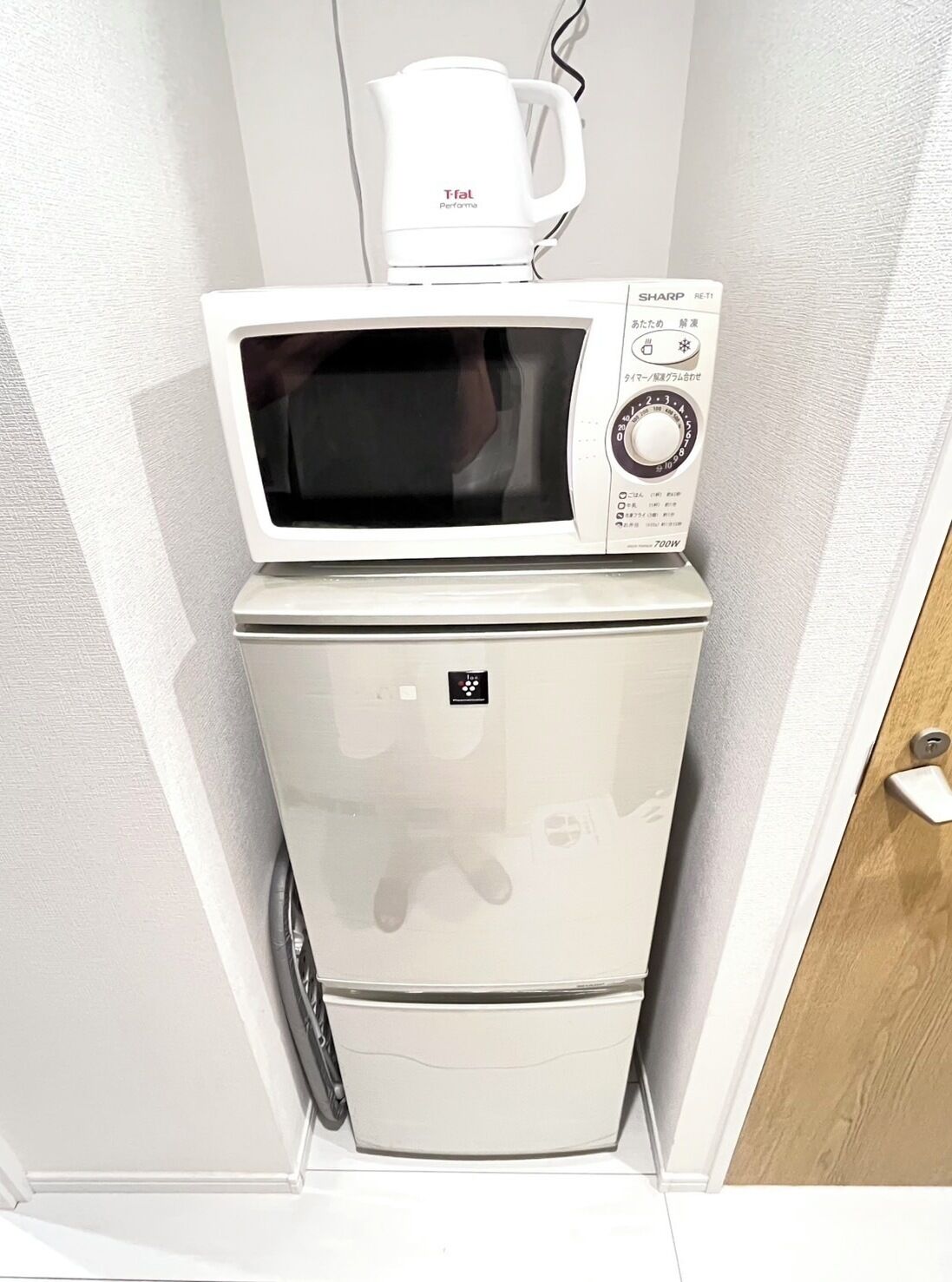 A compact kitchen with a microwave and a coffee maker on top of a refrigerator.