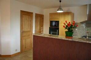 A kitchen with wooden cabinets, a microwave, an oven, a granite countertop, and a potted plant.
