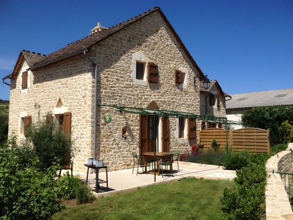 A stone house with a patio, outdoor seating, and a garden.