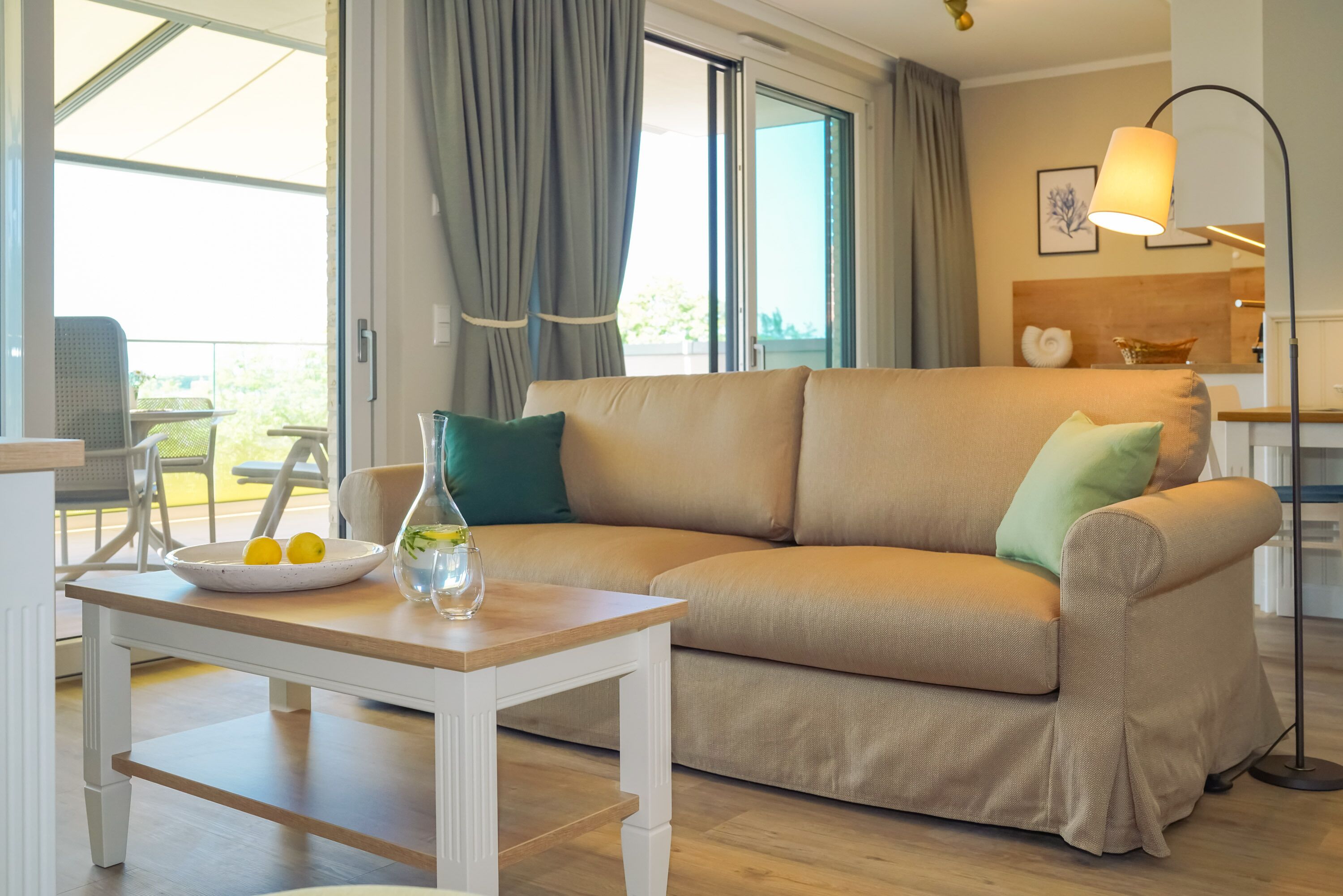 Ein modernes Wohnzimmer mit einem beigefarbenen Sofa, einem Holztisch und einem Essbereich mit weißem Tisch und Stühlen.