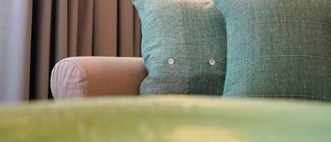 A green sofa with two matching cushions and a smaller, textured pillow.