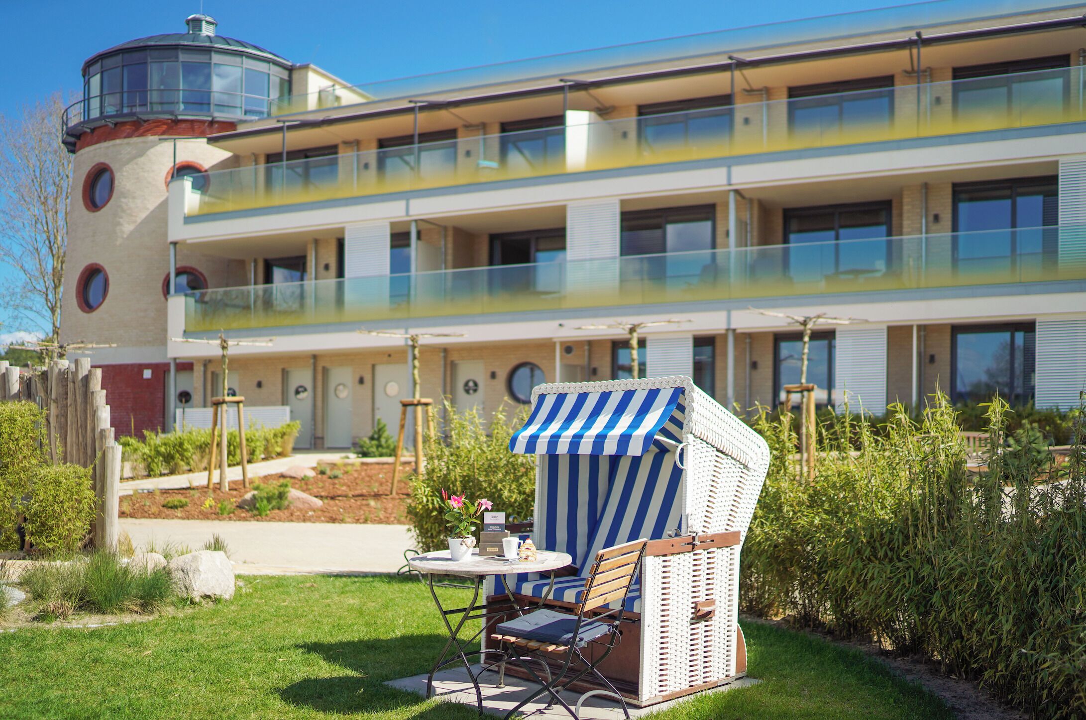 Un hôtel moderne doté d’une tour circulaire, d’une piscine sur le toit et d’un espace de détente sur la plage avec table et chaises.