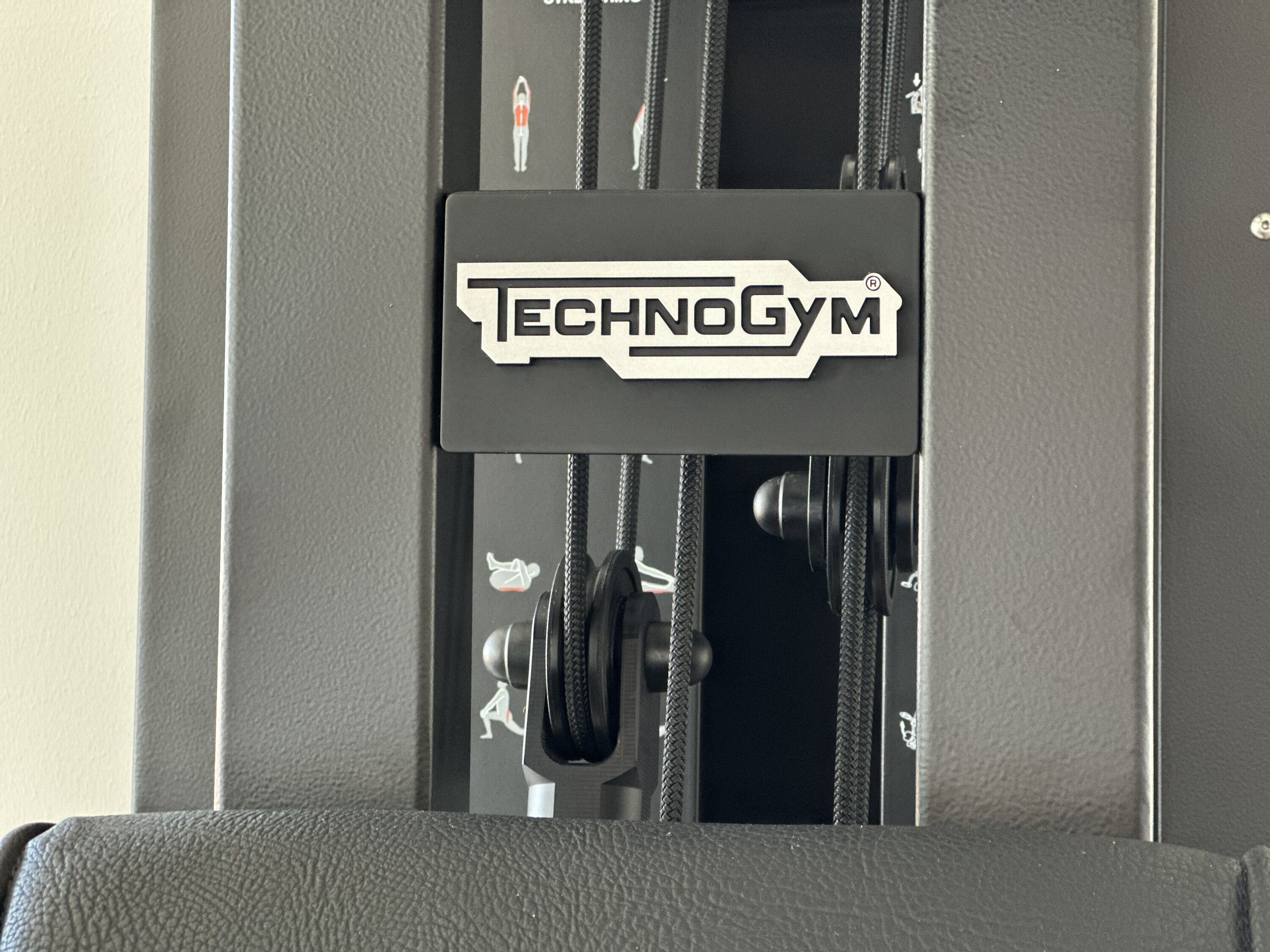 Un appareil de musculation noir avec un logo « TechnoGym » bien visible.