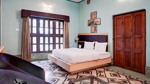 Un dormitorio con cama, armario, ventana con cortinas y ventilador de techo.