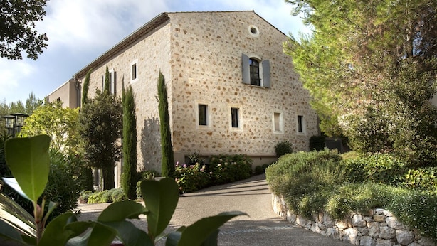 A stone building with a sloped roof, rectangular windows, and a stone pathway leading to the entrance.