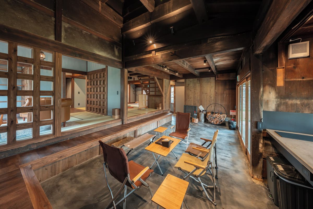 A traditional Japanese-style room with tatami flooring, wooden furniture, and a view of a garden through large windows.