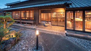A traditional Japanese building with a tiled roof, wooden structure, and a garden area with rocks and plants. - Kominka NOIE (Kushimoto)