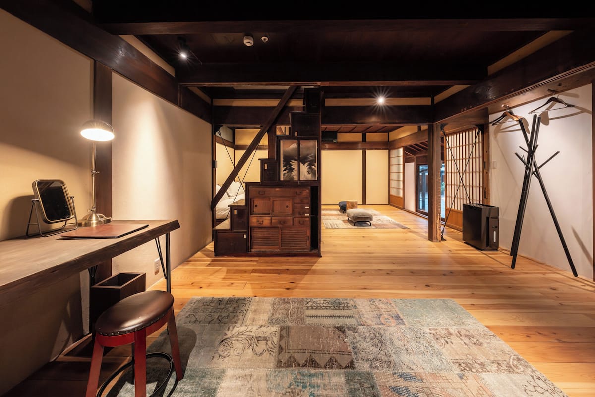 A spacious room with a wooden desk, a chair, and a large rug.