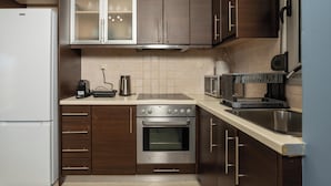 A modern kitchen with dark wood cabinets, a stainless steel oven, a microwave, and a coffee maker. - Zen City Beach Apartment (Chania)