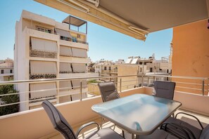 A balcony with a table and chairs, overlooking a residential area with multiple buildings. - Zen City Beach Apartment (Chania)