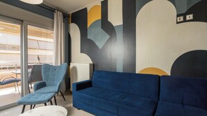 A modern living room with a blue sofa, a blue armchair, and a white table. - Zen City Beach Apartment (Chania)