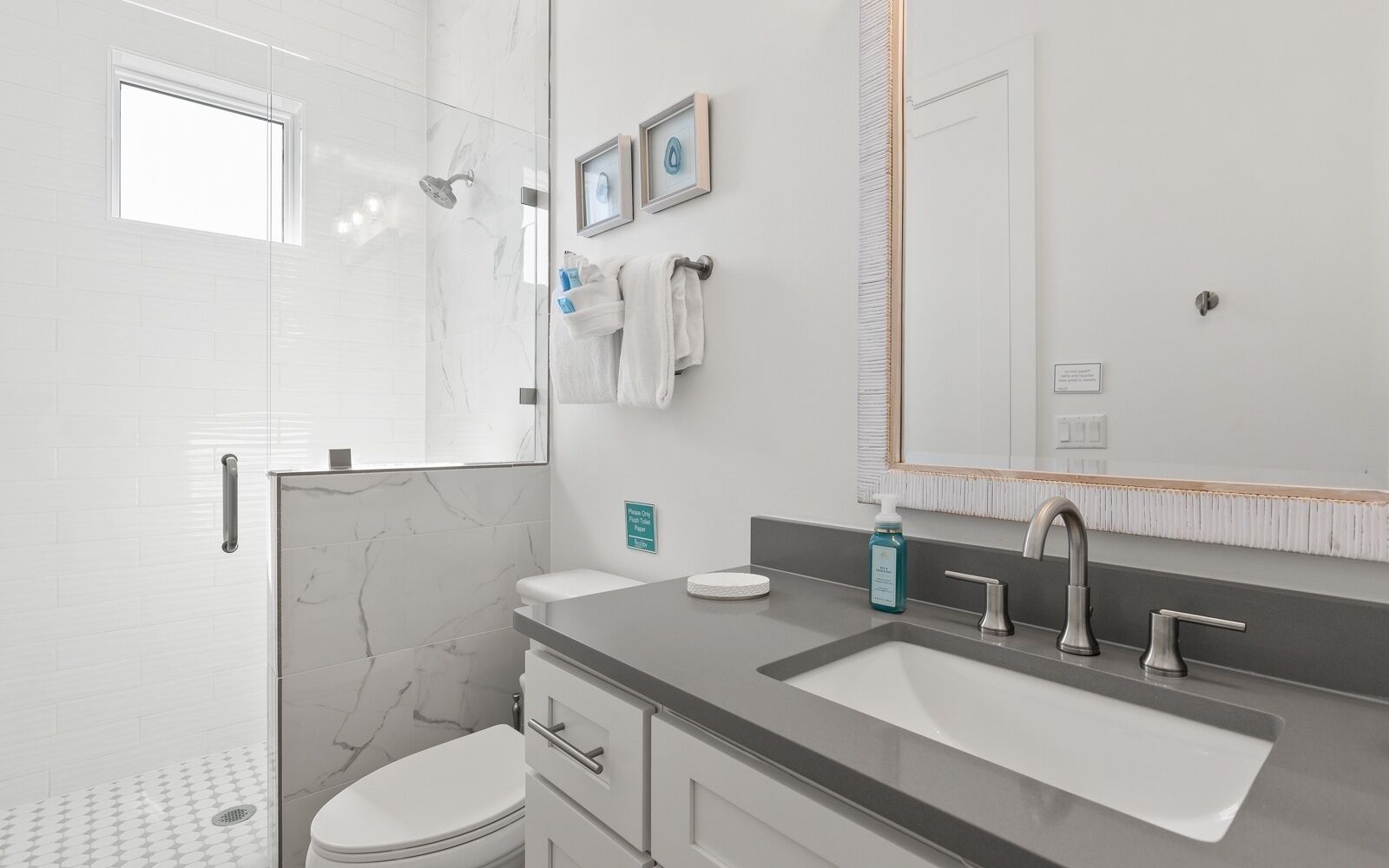 A modern bathroom with a glass shower enclosure, a toilet, a sink with a mirror, and a towel rack.