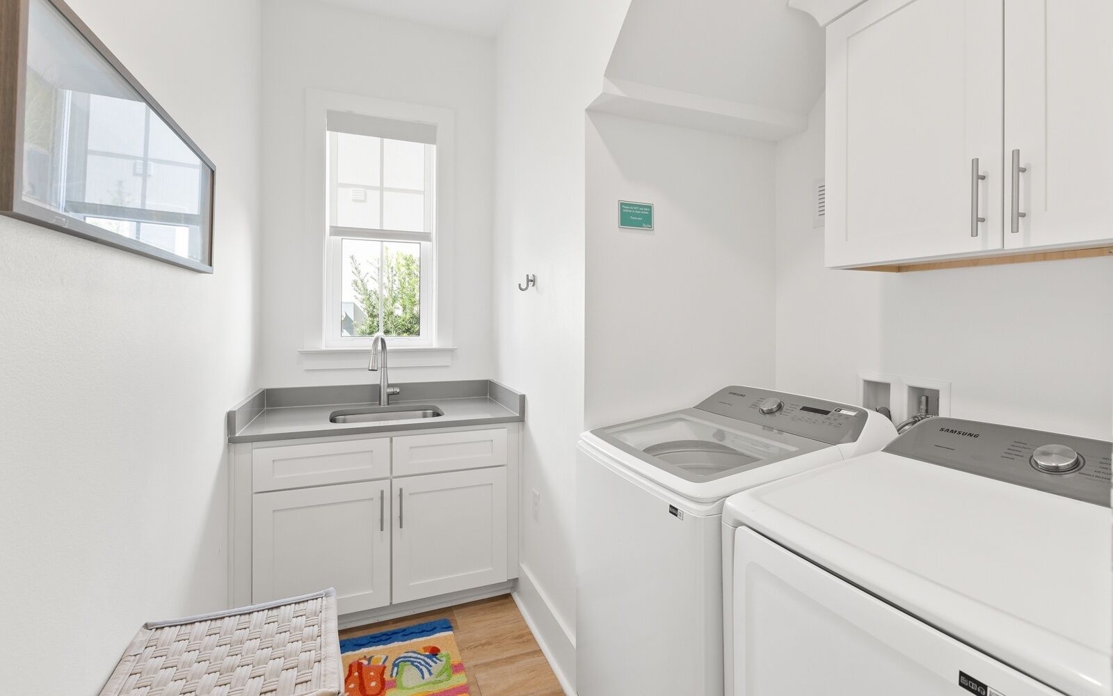 A compact kitchen with white cabinets, a sink, and a washing machine.