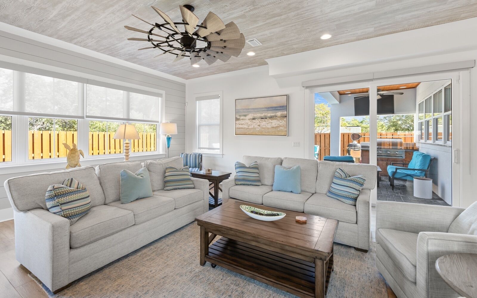 A spacious living room with a large sectional sofa, a wooden coffee table, and a ceiling fan.