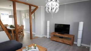 Ein modernes Wohnzimmer mit Fernseher, Holzmöbeln und einer außergewöhnlichen Deckenleuchte.