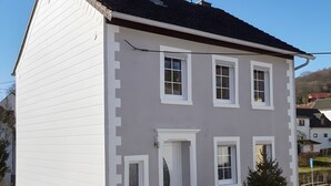 Ein zweistöckiges Gebäude mit weißer Fassade, dunklem Dach und mehreren Fenstern.