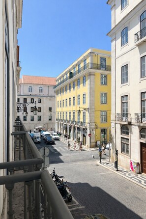 Straßenansicht mit Gebäuden, einer Kopfsteinpflasterstraße und einem Motorrad, das am Bürgersteig parkt.