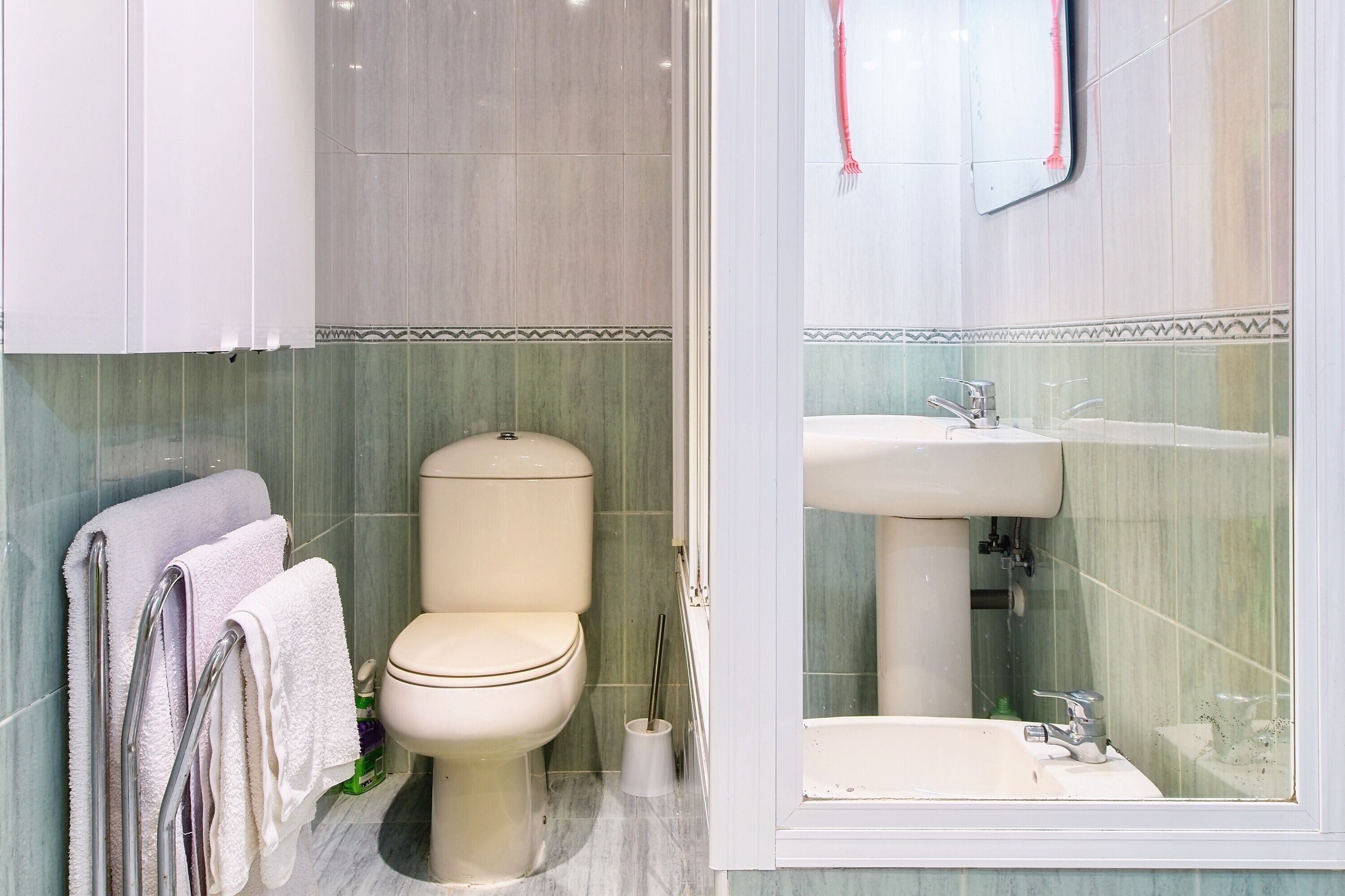 Een badkamer met toilet, wastafel en handdoekrek.