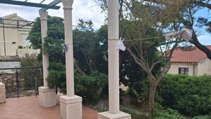 A covered outdoor area with concrete pillars, a tiled floor, and a garden with various plants. - Villa Jagoda (Orebic)