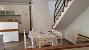 A dining area with a table and chairs, a kitchen in the background, and a staircase. - Villa Jagoda (Orebic)