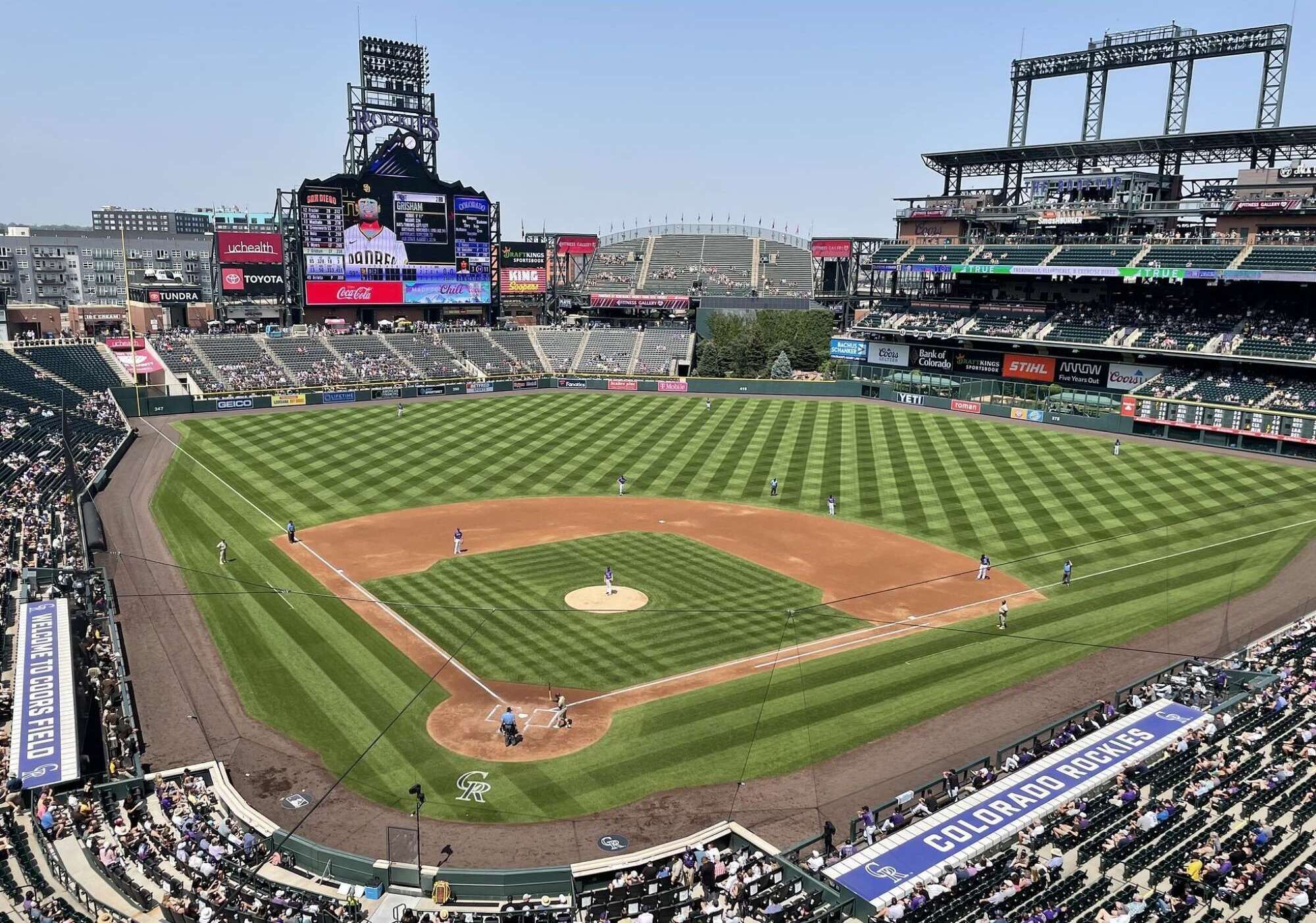 A baseball stadium with a large screen, advertisements, and a clear view of the field.
