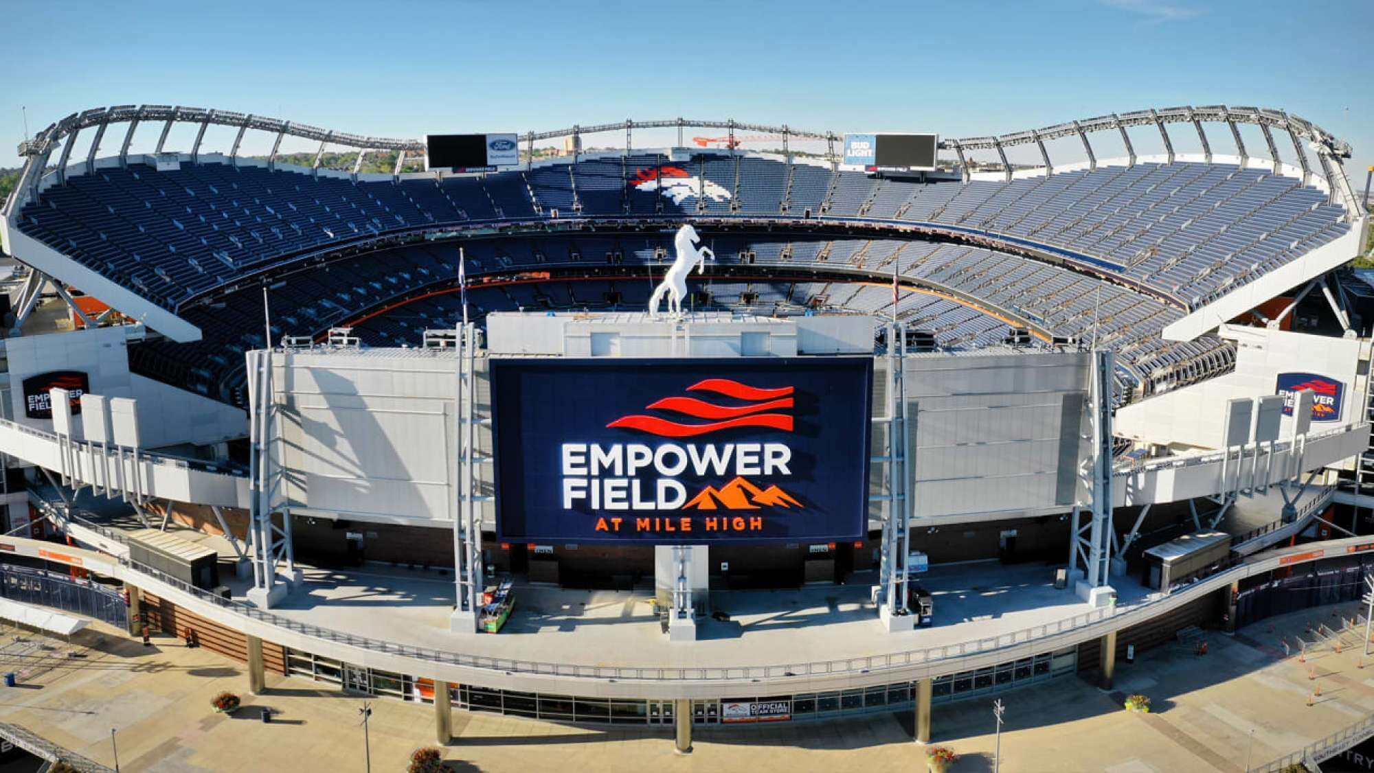 A stadium with a large digital display advertising 'EMPOWER FIELD AT MILE HIGH'.