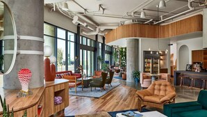 A spacious lobby with a high ceiling, exposed ductwork, and large windows offering views of the outdoors. - Steps to Mission Ballroom + Kitchen. Bar. Playroom (Denver)