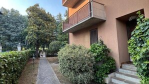 Un edifici amb un camí de pedra que condueix a una porta, envoltat de verdura i un cel serè.