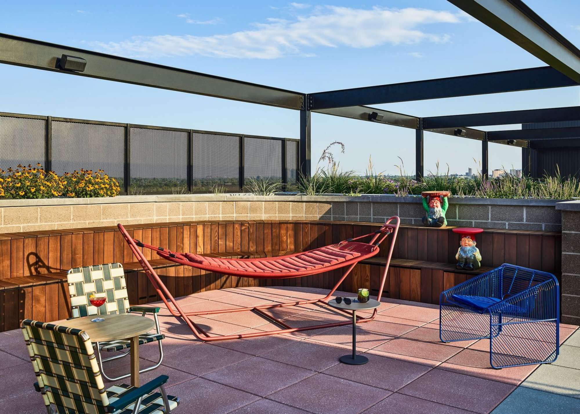 An outdoor patio with a hammock, a table with chairs, and a blue chair.